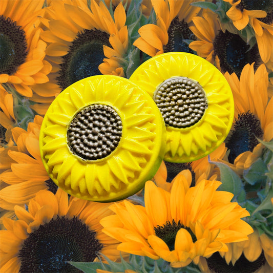 Two yellow sunflower-shaped objects with metallic centers on a background of sunflowers.
