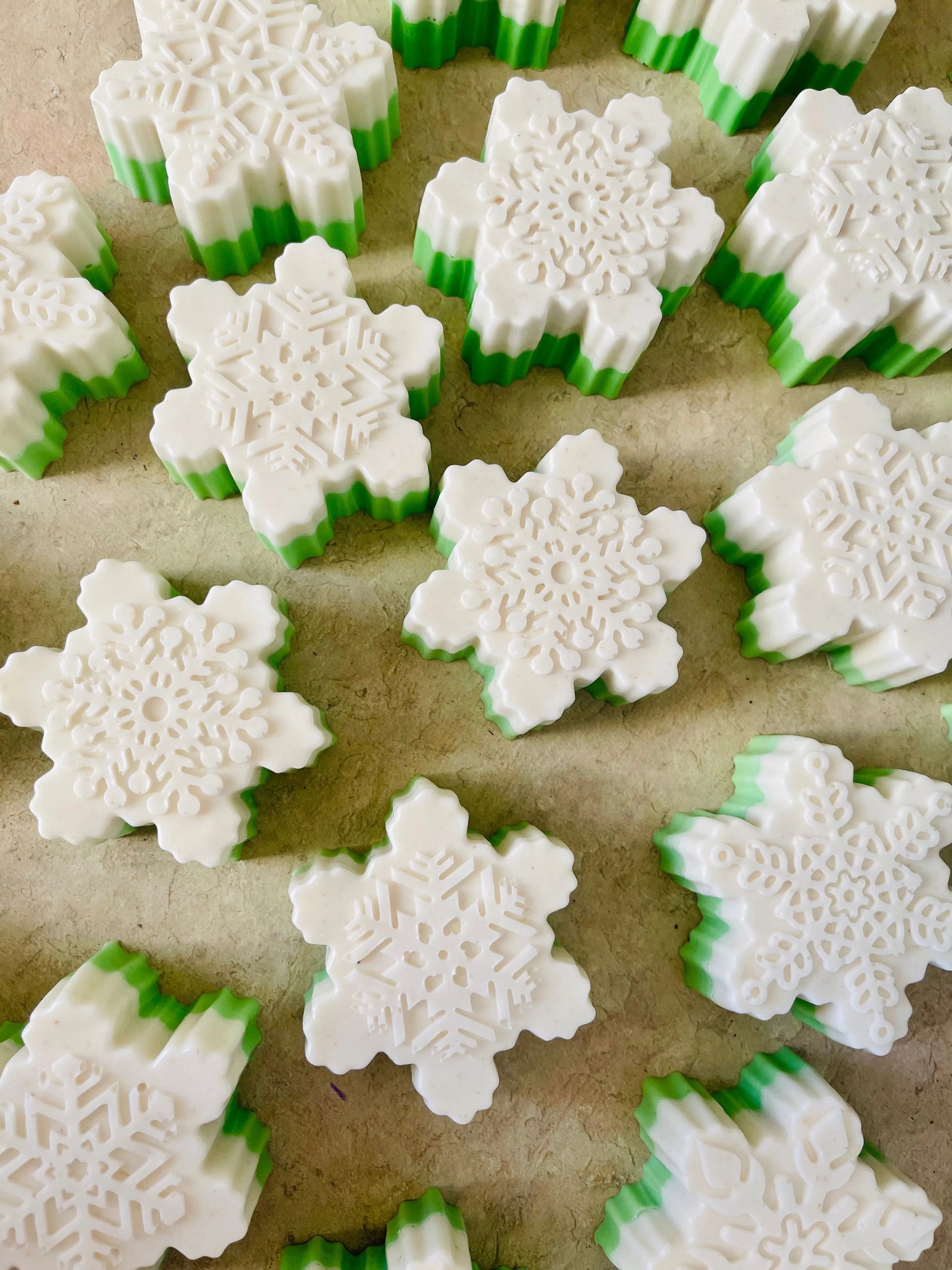 Snowflake-shaped cookies with green and white icing on a baking sheet.