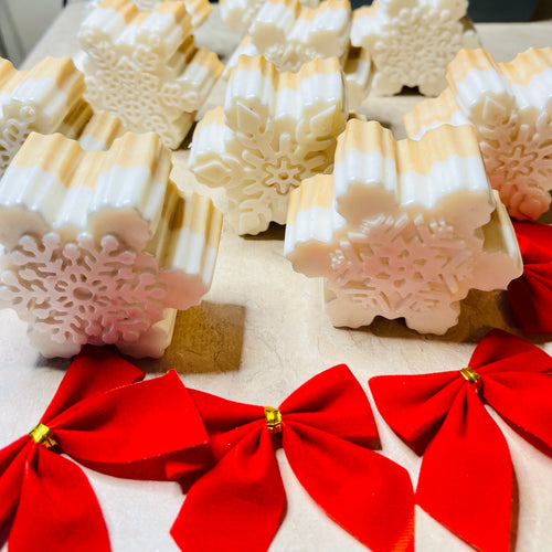 Snowflake-shaped soap bars with red bows on a white surface