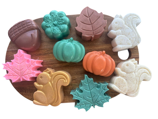 Set of colorful soap shapes including acorns, leaves, and squirrels on a wooden tray.