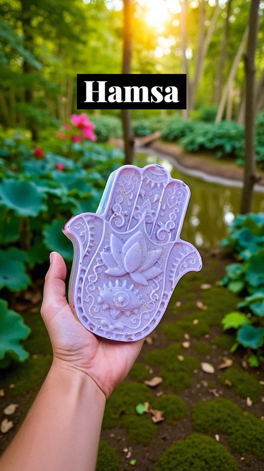 Hand holding a Hamsa hand symbol with a garden in the background