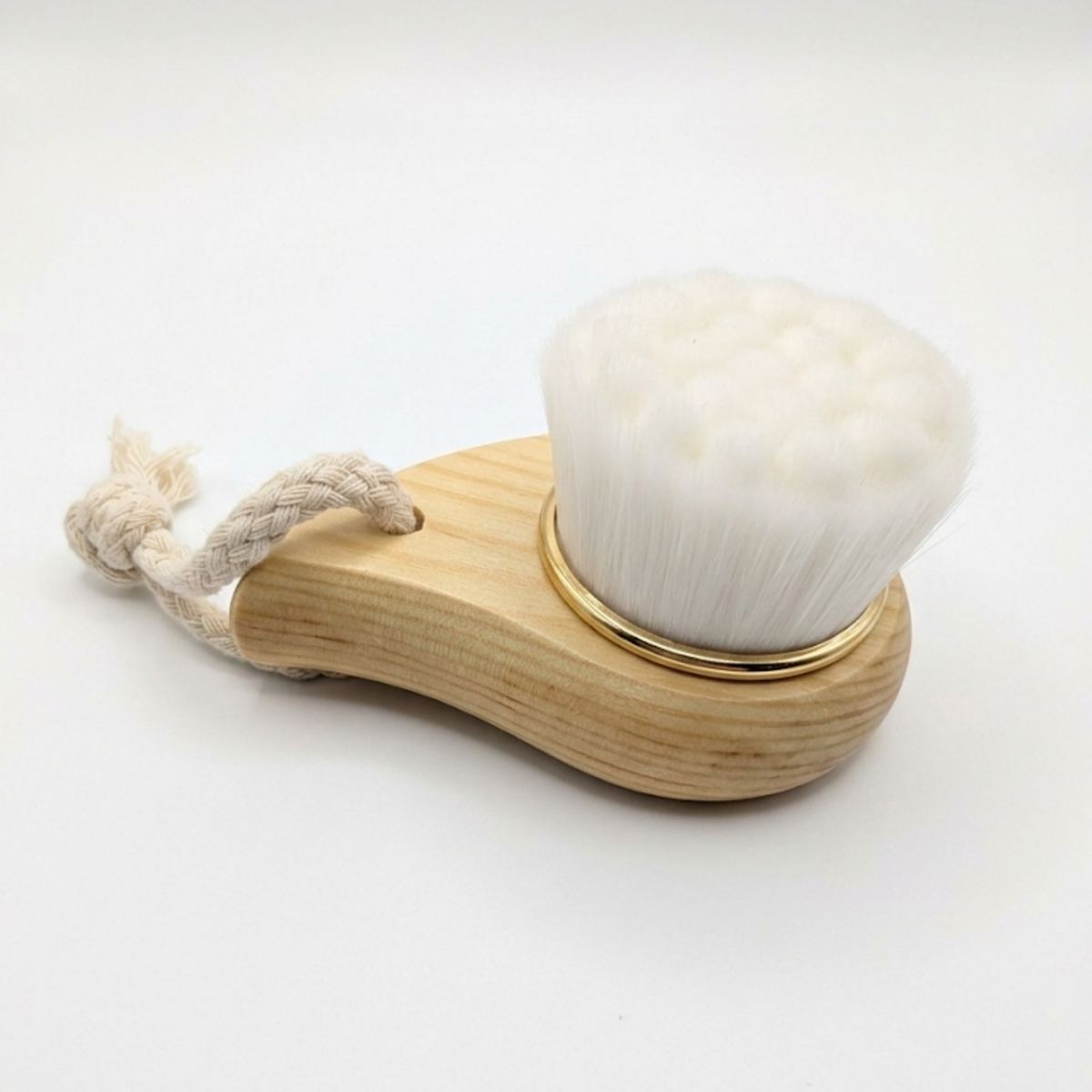 Facial cleansing brush with soft bristles and a wooden handle on a white background
