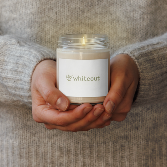 Person holding a candle labeled 'whiteout' with a blurred background