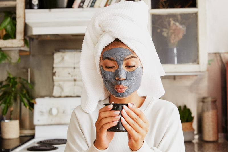 Woman applying a facial mask in a kitchen setting